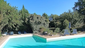A swimming pool with lounge chairs and a stone wall. - Élégance Périgourdine (Beaumontois en Périgord)