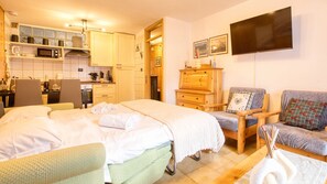 Ein Hotelzimmer mit Bett, Sessel, Sofa, Fernseher und einer Küchenzeile.
