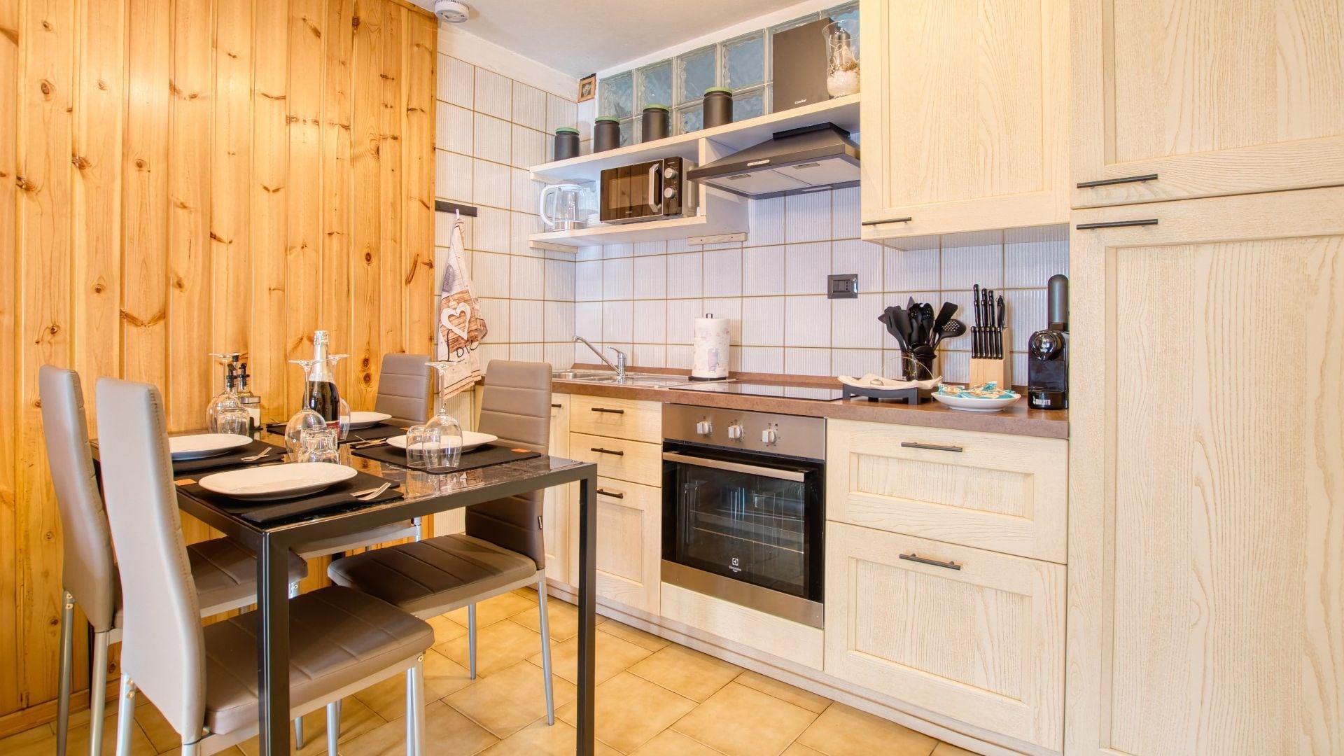 Eine moderne Küche mit Holzvertäfelung, einem Esstisch mit Stühlen und einem eingebauten Backofen.
