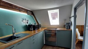 A compact kitchen with a sink, stove, and cabinets. - Lütt Stuuv im historischen Flensburger Hafen (Flensburg)