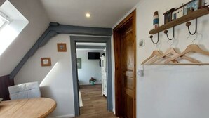 A room with a wooden table, a door, a coat rack, and a hallway leading to another room. - Lütt Stuuv im historischen Flensburger Hafen (Flensburg)