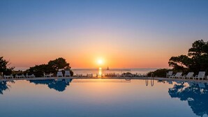 A pool with a sunset view, lounge chairs, and a clear sky. - Apartment Mare 8 by Interhome (Porto Cervo)