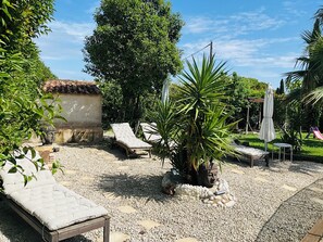 A garden with a Buddha statue, two lounge chairs, a palm tree, and a small play area. - 4-Star Suite - Garden, Pool, Small Events Available (Solliès-Pont)