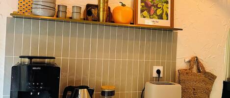 A kitchen with a coffee maker, toaster, kettle, and a framed picture on the wall.
