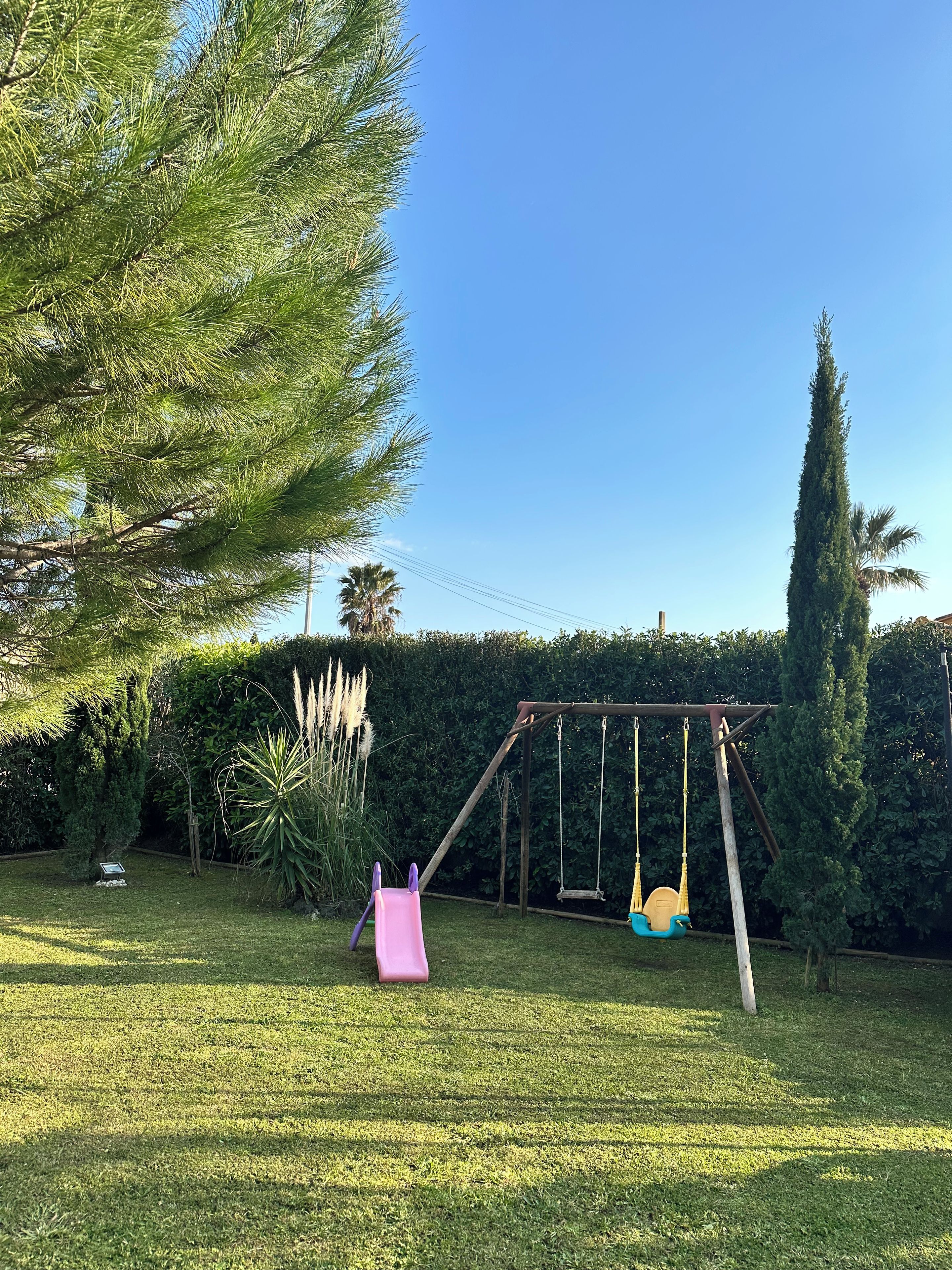 Un jardin avec une balançoire, un toboggan et une pelouse bien entretenue.