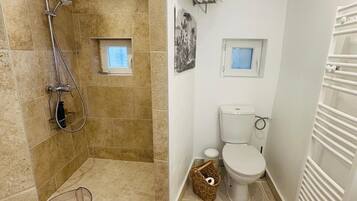 Une salle de bain avec une douche, des toilettes et un radiateur.