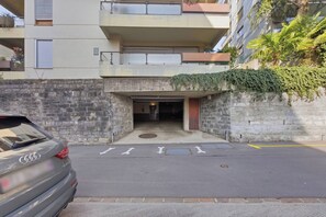 En modern byggnad med en fasad av sten, en parkerad bil framför och en tydlig entré.