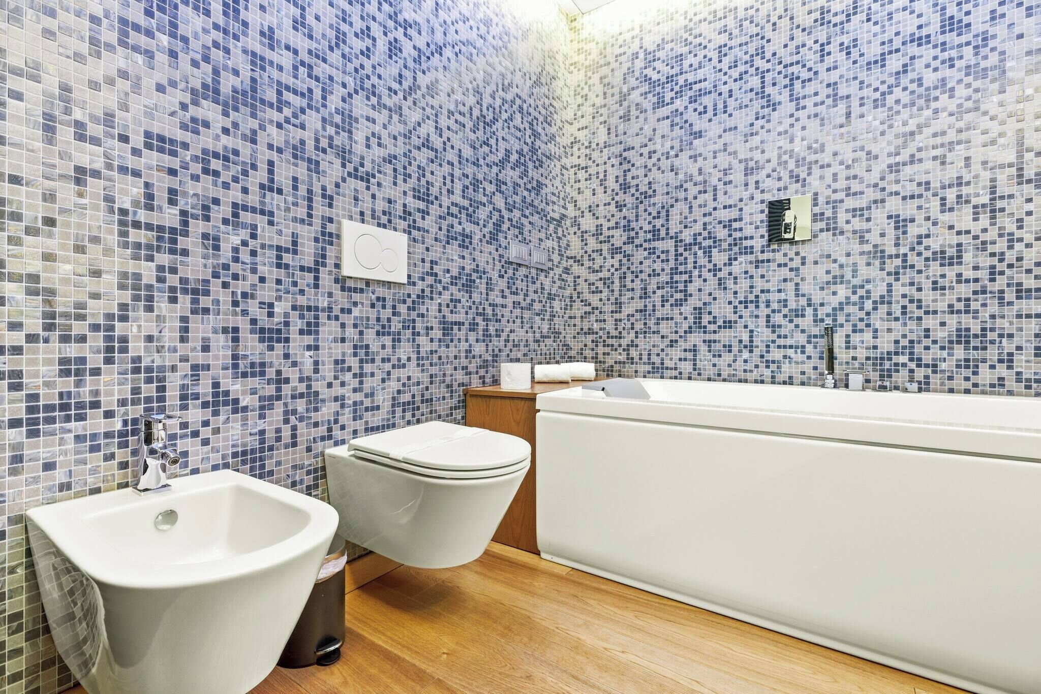 A bathroom with a bidet, toilet, and bathtub.