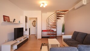 A modern living room with a TV, sofa, and a spiral staircase. - Apartment Skroce (Zaton)