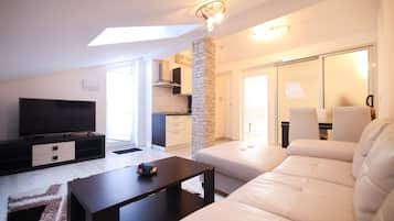 Apartamento conforto, vista parcial para o mar | Área de estar | Smart TV 100 cm com canais via satélite