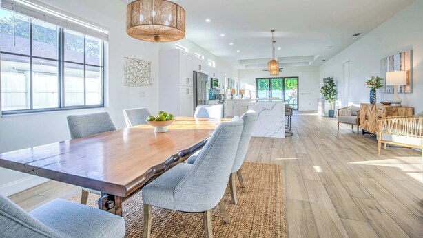 A spacious kitchen with modern appliances, a large dining table, and a view of the outdoors. - Barletta 4BR Pool Home | Bikes, BBQ & Golf (Naples)