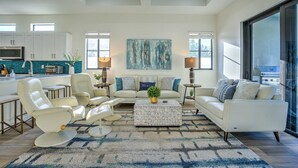 A modern living room with a sofa, chairs, a coffee table, and a painting on the wall. - Barletta 4BR Pool Home | Bikes, BBQ & Golf (Naples)