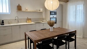 Een moderne keuken met een houten eettafel, zwarte stoelen, een hanglamp en een inbouwoven.