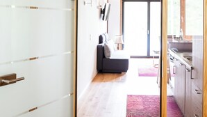 Een modern interieur met een houten plafond, een keuken met houten kastjes, een grijze bank en een groot raam.