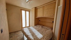 Une chambre à coucher avec un lit, une armoire en bois et une fenêtre.