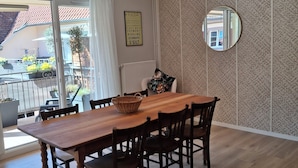 A dining area with a wooden table and chairs, a hanging light fixture, a mirror, and a patterned wall. - Gîte Le Schopf - 3 bedrooms - free parking - 25 km from Strasbourg (Scharrachbergheim-Irmstett)