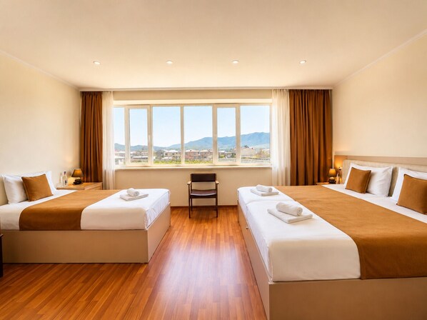 Ein Hotelzimmer mit zwei Betten, einem Schreibtisch und Blick auf die Stadt.