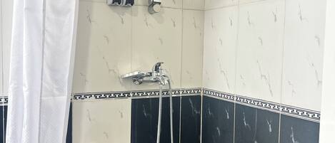 Zona de ducha con cabezal de ducha manual, llave de pared y panel de control con etiquetas 'CUERPO' y 'CABELLO'.