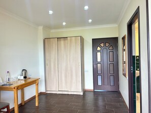 Un couloir avec une table en bois, une armoire et une porte ornée de panneaux décoratifs.