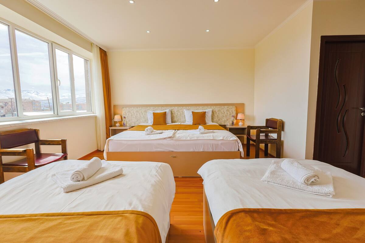 Una camera d'albergo con due letti, una scrivania e una sedia.
