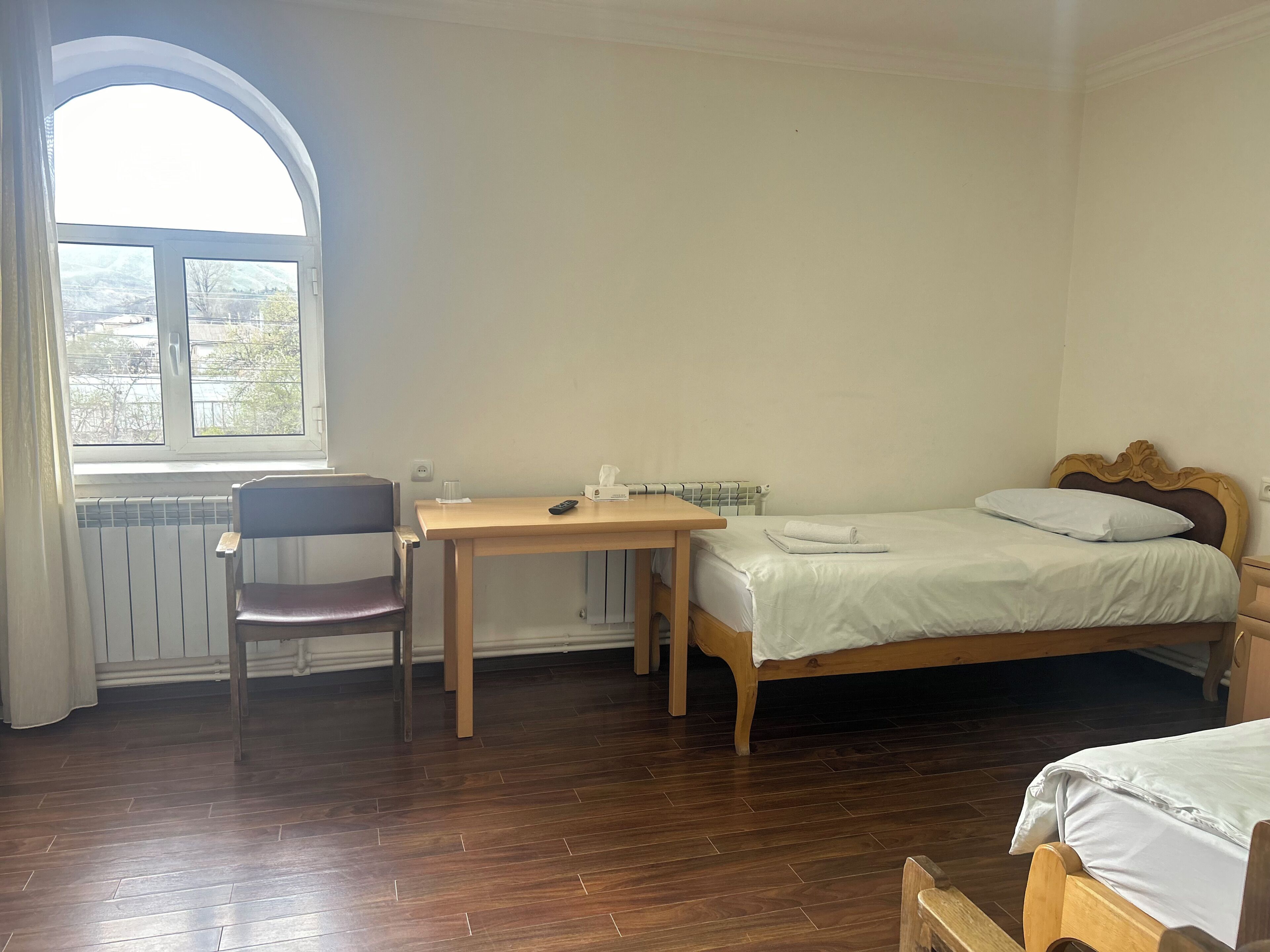 A room with a bed, a chair, a table, and a window.