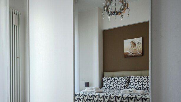 A modern bedroom with a bed, a chandelier, and a painting on the wall. - SEA FRONT Gorgeous newly renovated beachfront apartment (Pesaro)