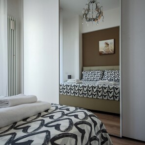 Een moderne slaapkamer met een bed, een kroonluchter en een schilderij aan de muur.