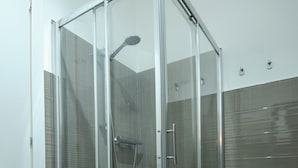 A glass-enclosed shower stall with a handheld showerhead and a floor drain. - SEA FRONT Gorgeous newly renovated beachfront apartment (Pesaro)