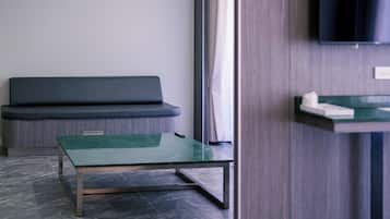 Une pièce moderne avec une table en verre vert, un canapé foncé et un téléviseur fixé au mur.