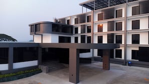 Een modern, meerlaags gebouw met een plat dak, grote ramen en een overdekt buitengebied.