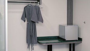 Ein Badezimmer mit Handtuchhalter, einem Bademantel, einem kleinen Waschbecken und einem Spiegel sowie einem Schrank.