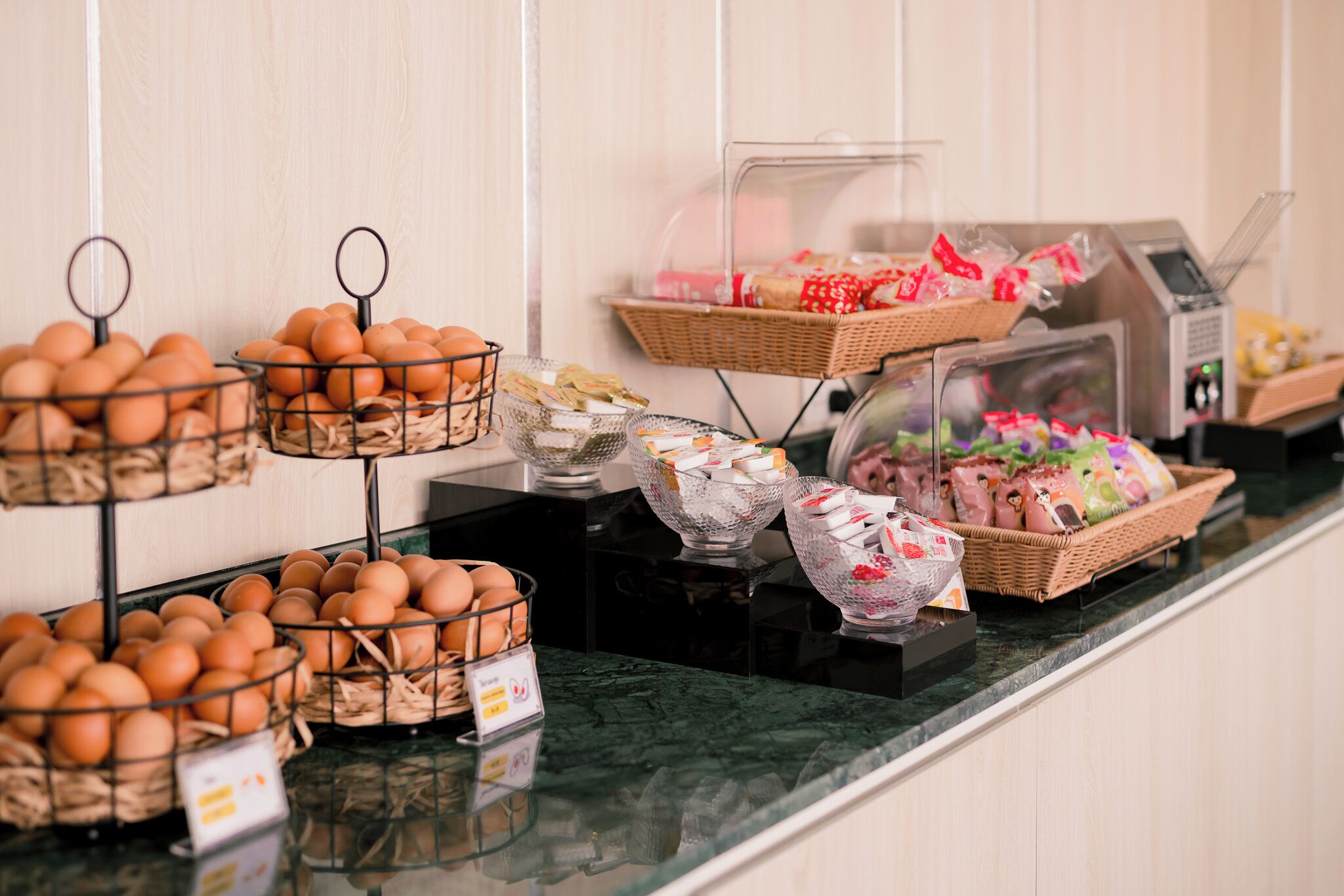 A breakfast buffet with various food items including eggs, pastries, and packaged goods.