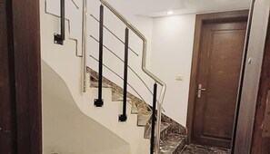 Eine Treppe mit Metallgeländern und Marmorstufen, die zu einer Holztür führt.