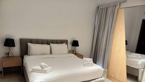 Een hotelkamer met een groot bed, twee nachtkastjes met lampen, een spiegel en een gordijn.