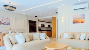 A modern living room with two beige sofas, a round coffee table, and a chandelier. - Luxury 3BR • Lakeview Residence • Premium Stay (القاهرة)