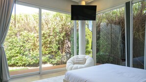 Un dormitorio con una cama grande, una silla y un televisor montado sobre un pilar.