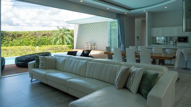 Una sala de estar moderna con sofá blanco, comedor y cocina.