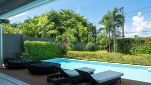 Zona junto a la piscina con sillones de descanso y una terraza de madera.