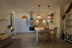 A modern kitchen with white cabinets, a dining table with chairs, and pendant lights. - Haevn by the Sea, Water Room (Reußenköge)