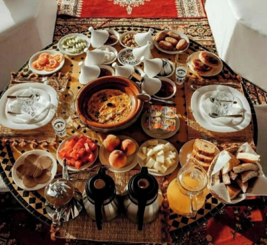 A round dining table with various dishes, utensils, and teapots.