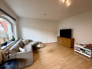 Un soggiorno moderno con un divano, un tavolino rotondo, una TV e un mobiletto in legno.