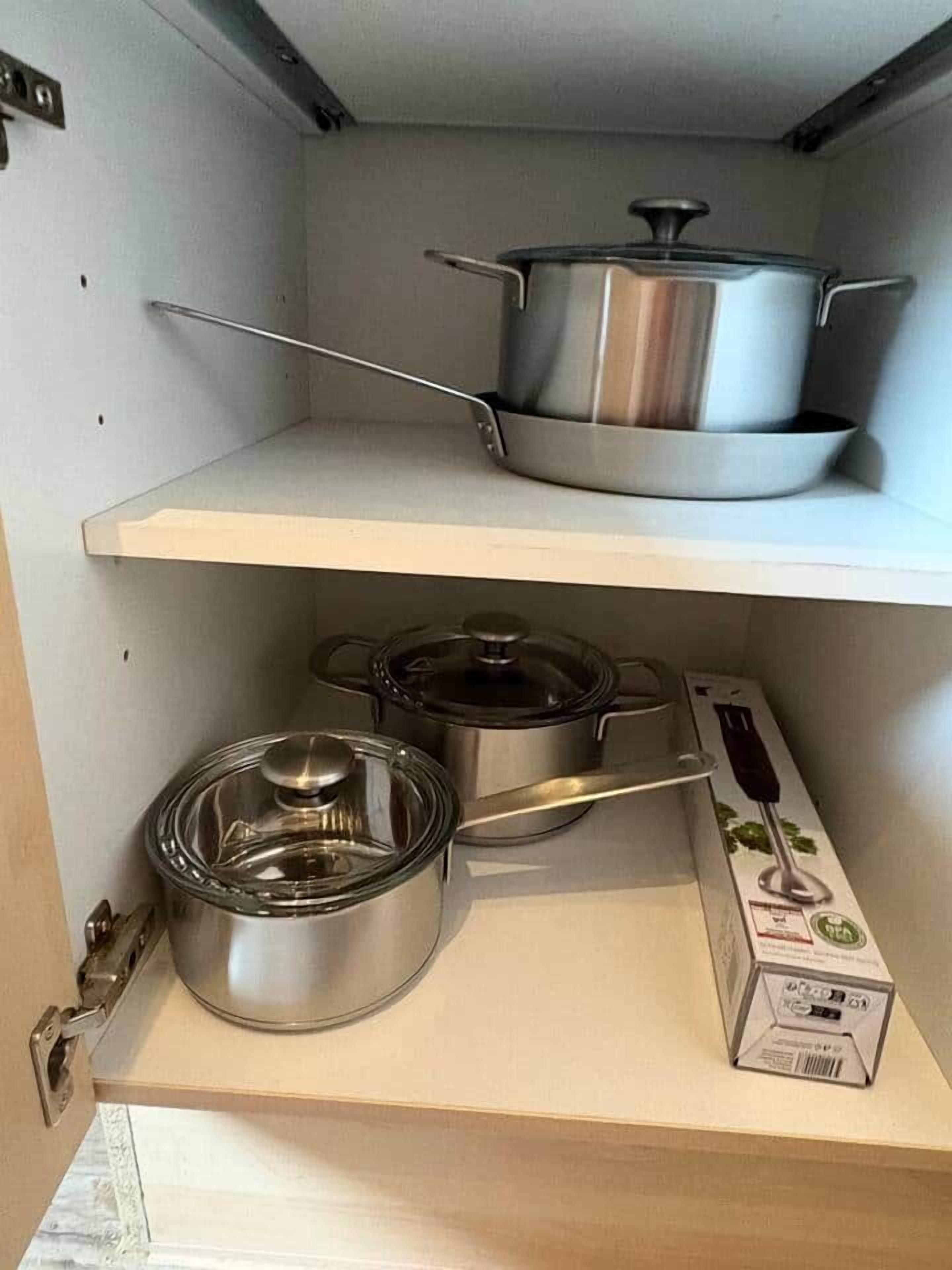 A kitchen with stainless steel cookware on shelves, including pots and pans.