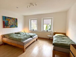Ein Zimmer mit zwei Betten, einem kleinen Tisch und einer Heizung.