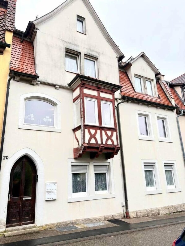 A building with a bay window, a wooden door, and a number '20' on the wall.
