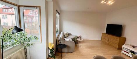 A modern living room with a sofa, a dining table, and a television.