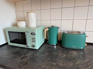 A kitchen with a microwave, toaster, and a kettle on a dark countertop. - A Cozy Stay in the Heart of Rothenburg—A Dream Apartment (Rothenburg ob der Tauber)