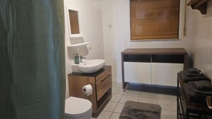 Et badeværelse med toilet, håndvask, vaskebord og håndklædestang.