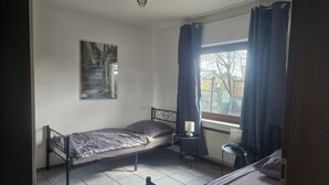Et lille værelse med en enkeltseng, et vindue, en radiator og et billede hængt på væggen.