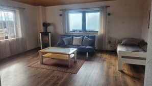 En hyggelig stue med sofa, sofabord, lille TV og en seng.