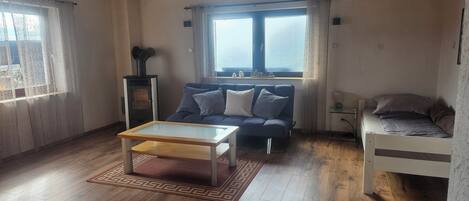 Una sala acogedora con un sofá, una mesa de centro, un televisor pequeño y una cama.
